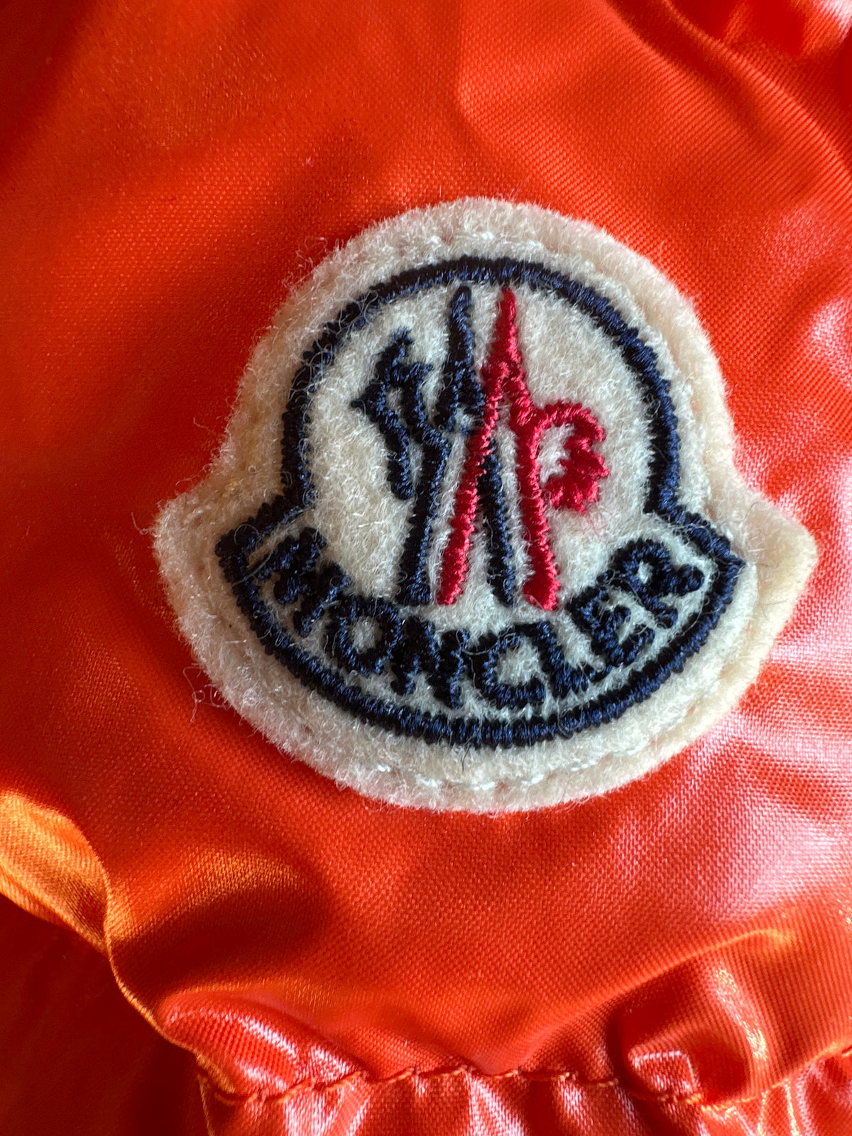 Moncler Designer-Baby-Daunenjacke orange, 12-18 Monate, Ärmelansicht seitlich Moncler-Logo