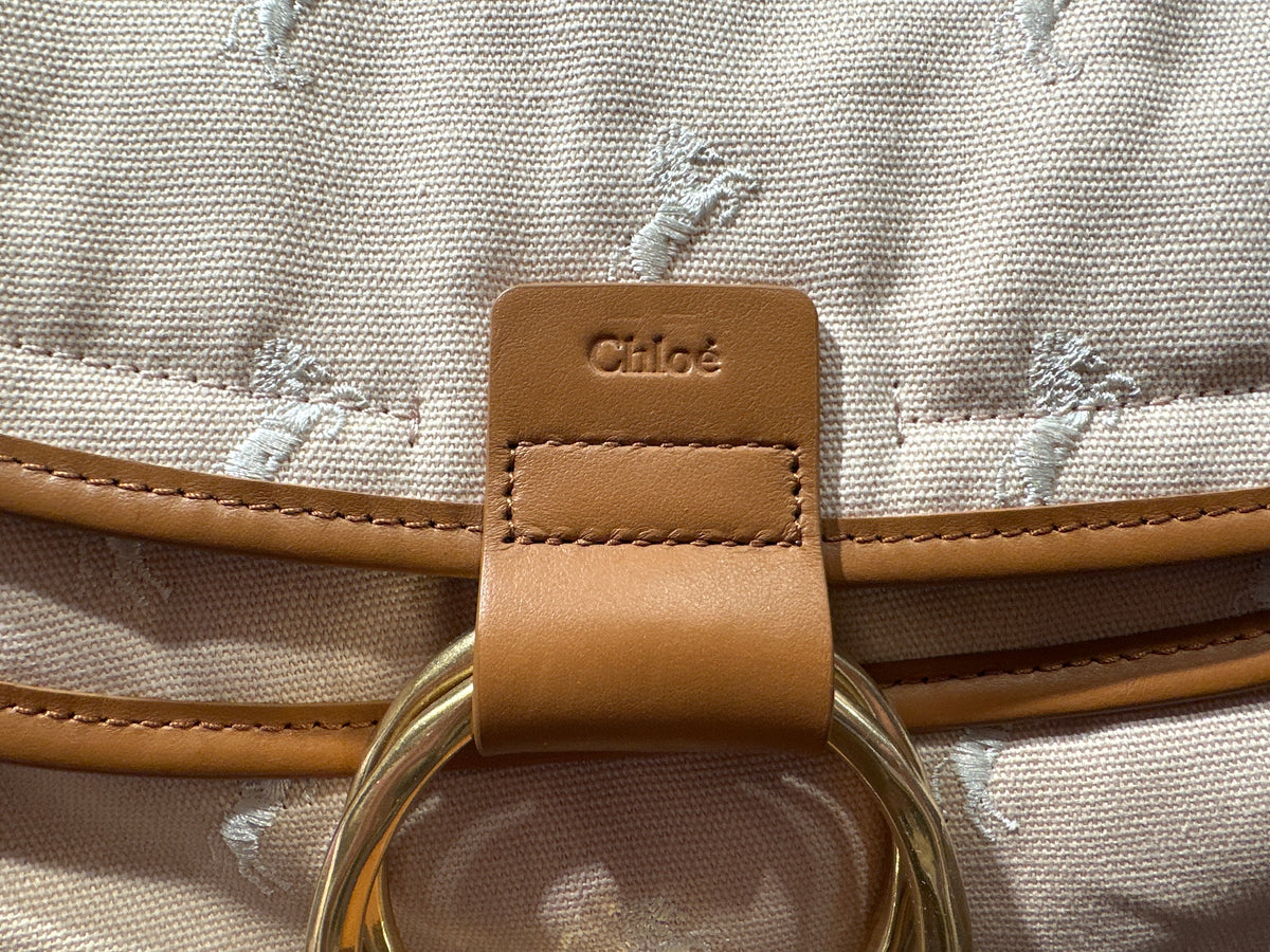 Chloe` Wickeltasche altrosa, Detail der braunen Verschlusslasche mit Markenprägung und goldfarbenem Ring